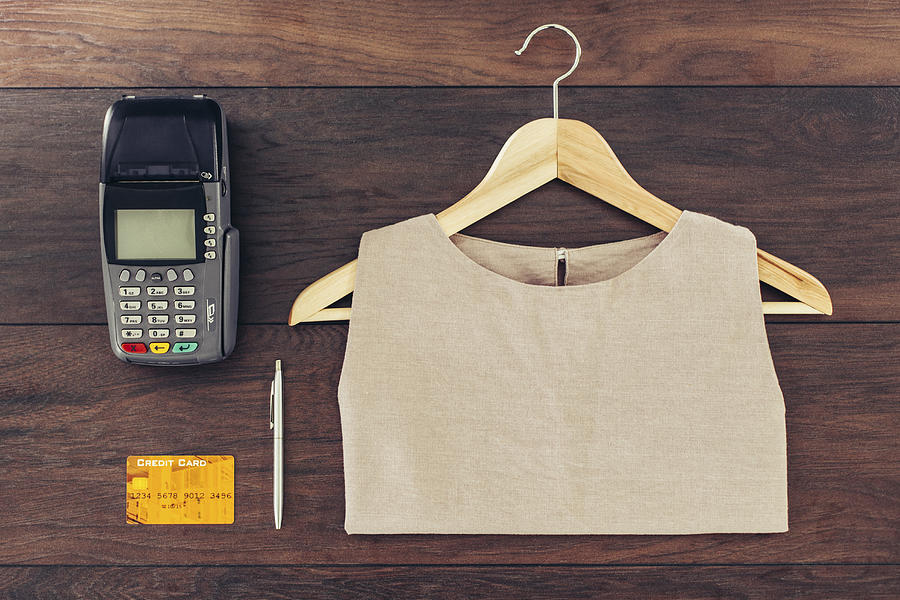 Shirt on hanger, credit card and machine on store counter Photograph by Lumina Images