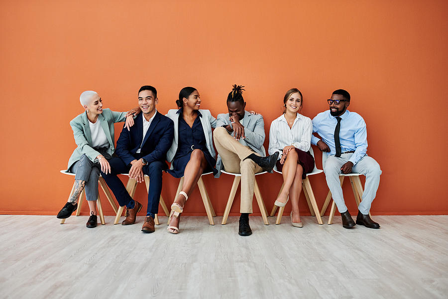 Shot of a group of businesspeople sitting against an orange background Photograph by Jeffbergen