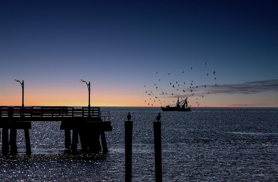 Shrimp boat beyond pier at Dusk Photograph by Darryl Brooks