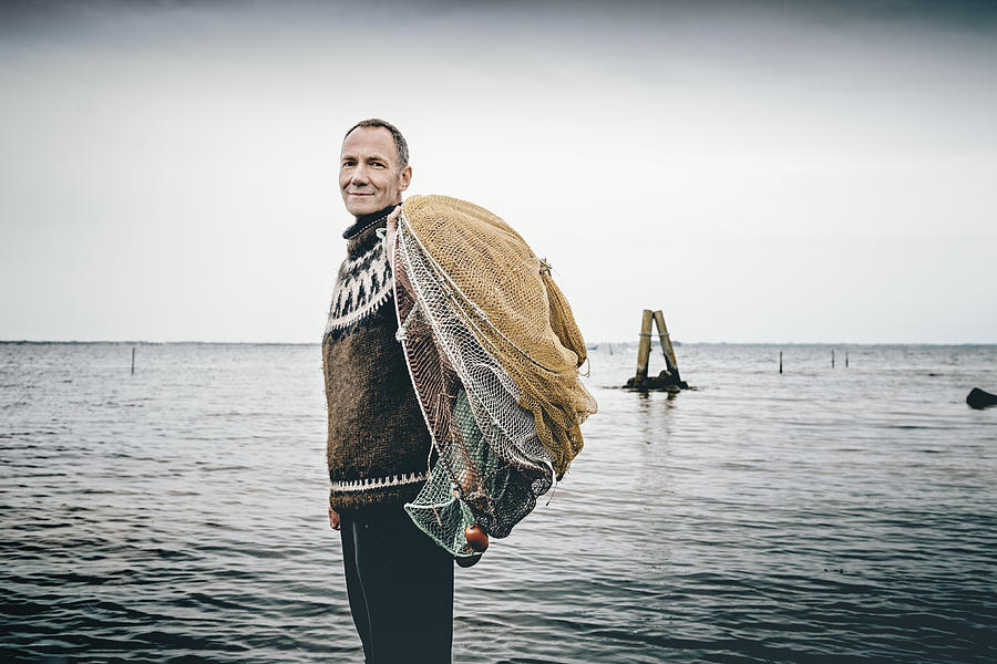 Shrimp fisherman setting out his nets in the sea. Photograph by ClarkandCompany