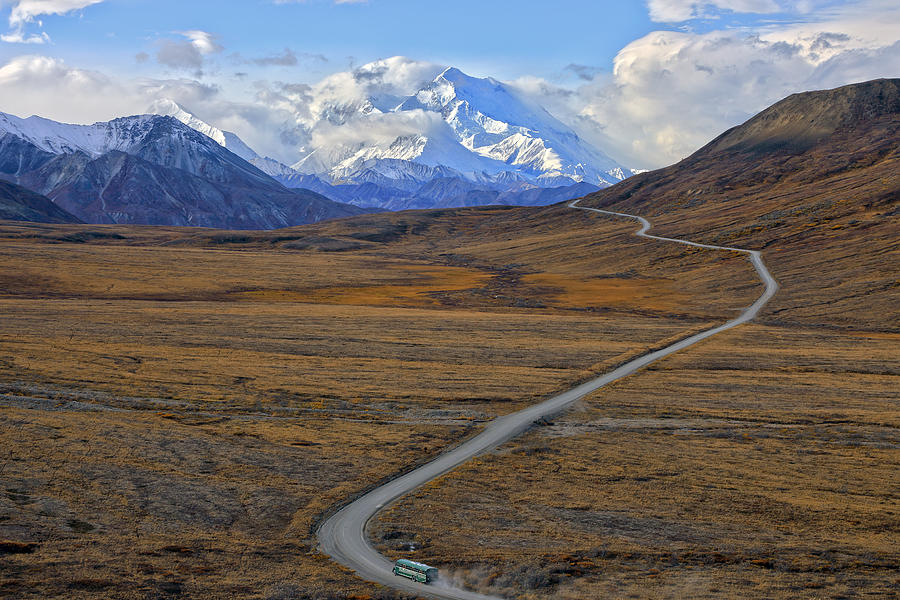 Shuttle bus driving on park road with Mount Denali in background Photograph by Rainer Grosskopf