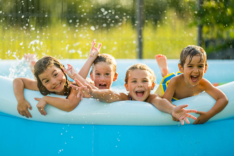 Siblings - four happy young kids in swimming pool Photograph by Amriphoto