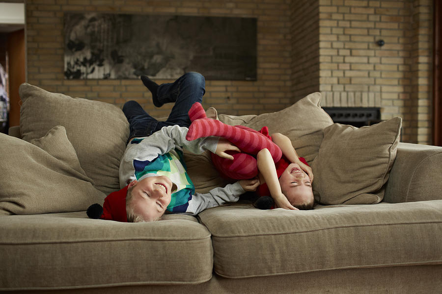 Siblings teasing each other in sofa Photograph by Klaus Vedfelt