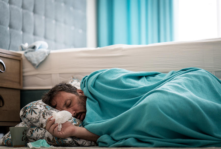 Sick man with fever on ground in bedroom Photograph by Jasmin Merdan