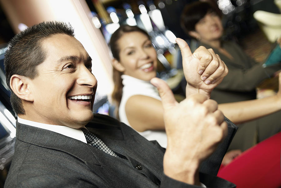 Side profile a mature man showing a thumbs up sign with his daughter beside him at a casino Photograph by Glowimages