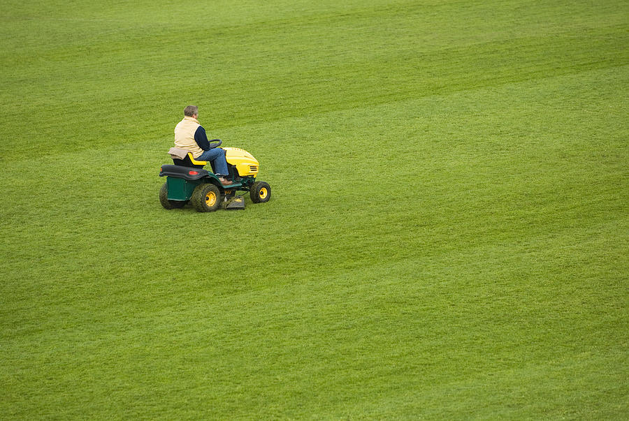 Side profile of a man mowing grass with a lawn mower in a field Photograph by Glowimages