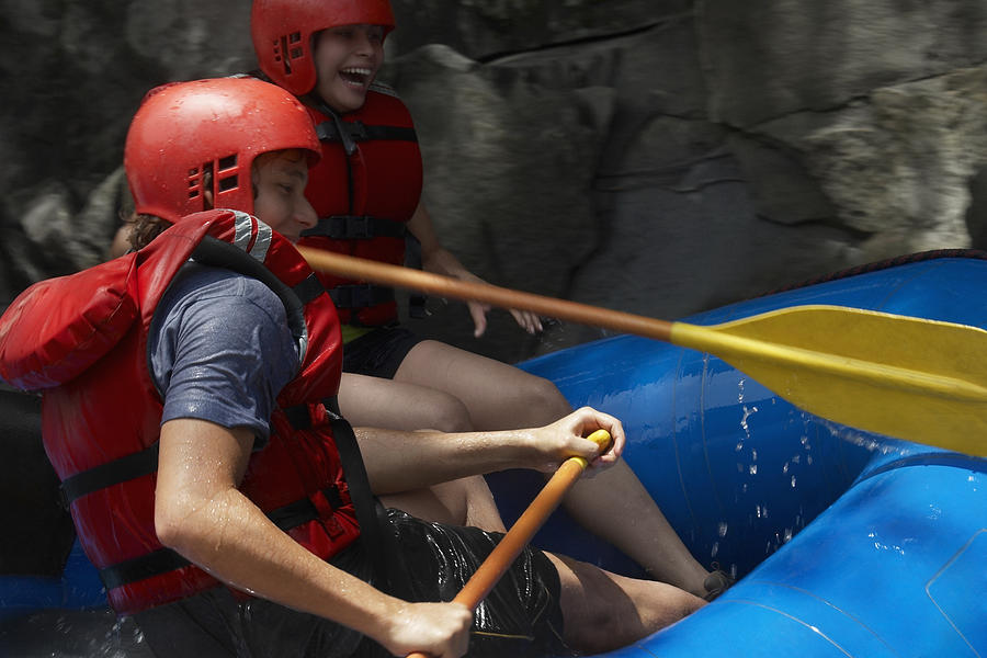 Side profile of a young couple rafting Photograph by Glowimages