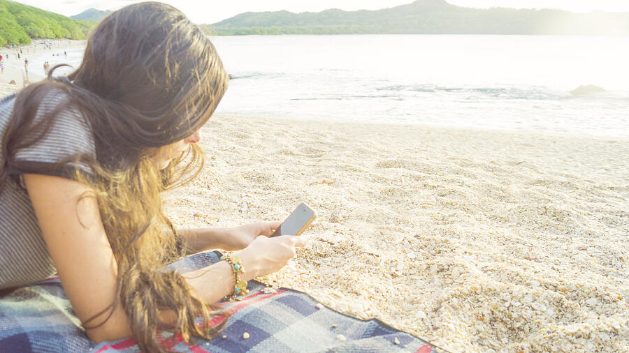 Side view of a woman texting in a smart phone on the beach with the sea in the background Photograph by Kryssia Campos