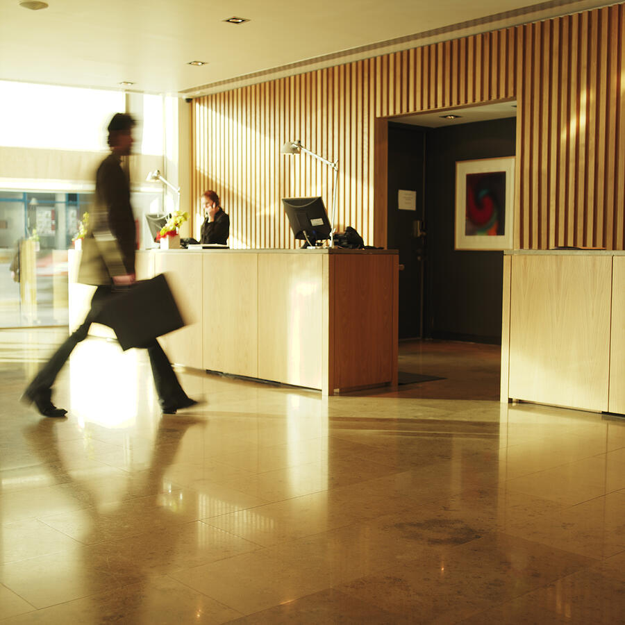 Side view of businessman walking past hotel reception Photograph by George Doyle