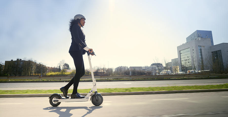 Side view of mature woman riding electric push scooter in city Photograph by Simonkr