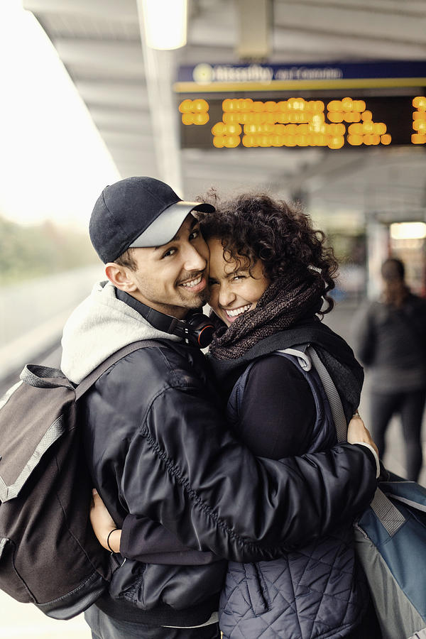 Side view portrait of happy couple embracing on subway platform Photograph by Maskot