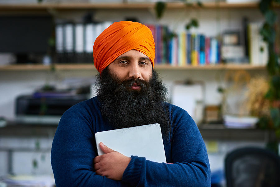 Sikh man holding laptop, looking at camera Photograph by 10000 Hours