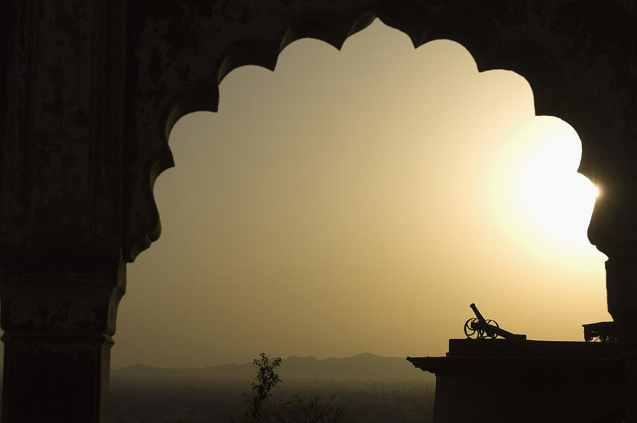 Silhouette of a cannon viewed through an arch at sunset, Neemrana Fort, Neemrana, Alwar, Rajasthan, India Photograph by PhotosIndia.com