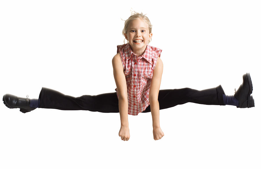 Silhouette Of A Caucasian Blonde Female Child  In Black Pants And A Plaid Shirt As She Jumps Up And Does The Splits Photograph by Photodisc