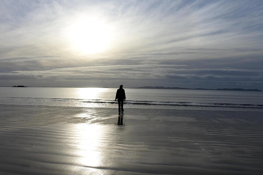 Silhouette of a person walking on a beach Photograph by Rafael Ben-Ari