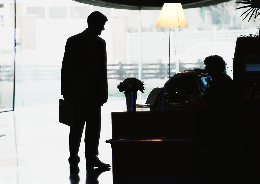 Silhouette of businessman standing in front of desk Photograph by Eric Audras