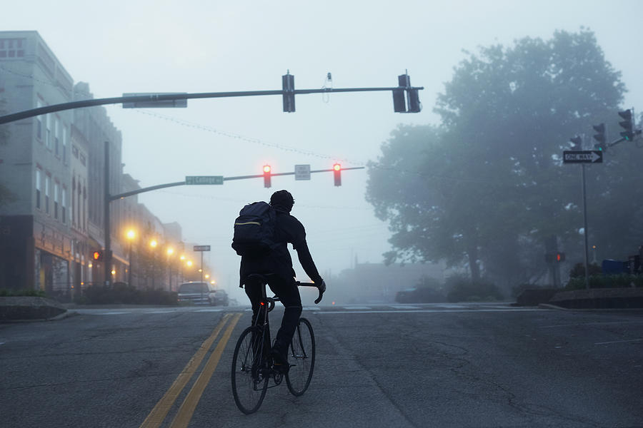 Silhouette of commuter riding bike during misty early morning Photograph by Patrick Fraser