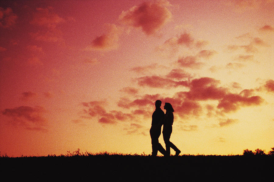 Silhouette of couple walking at dusk Photograph by Comstock
