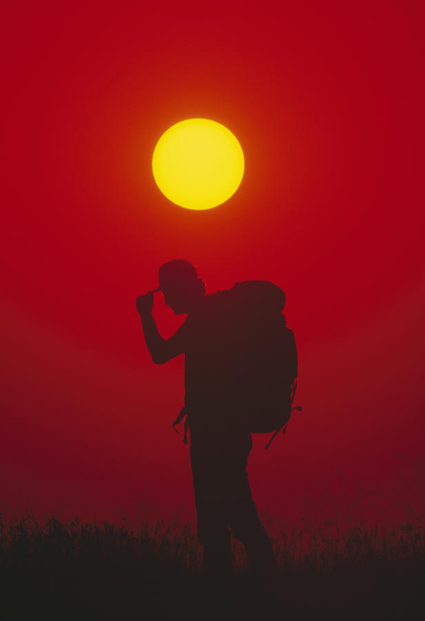 Silhouette of man carrying rucksack and holding cap, sunset Photograph by Murat Taner