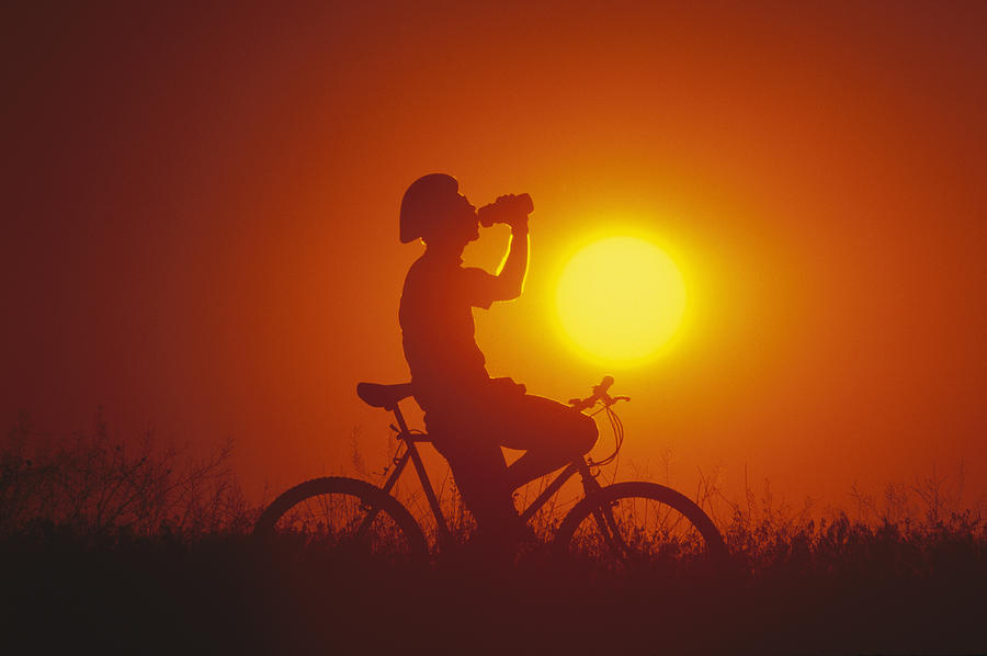 Silhouette of mountain biker drinking from bottle at sunset, side view Photograph by Murat Taner