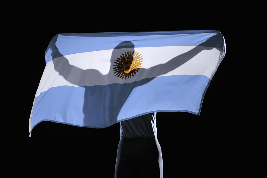 Silhouette of person holding flag of Argentina on black background Photograph by Paul Taylor