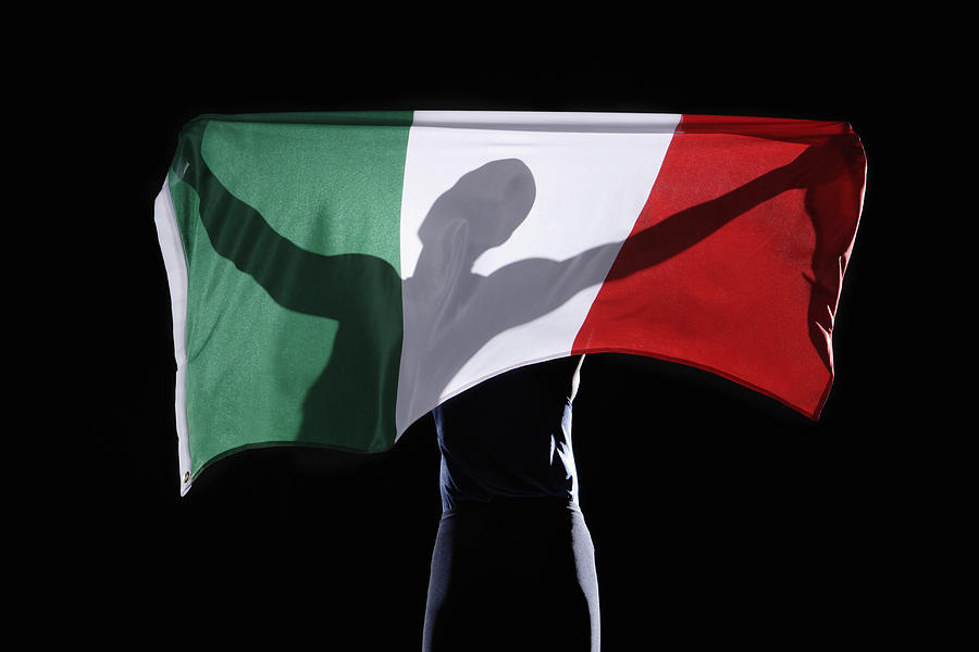 Silhouette of person holding flag of Italy on black background Photograph by Paul Taylor