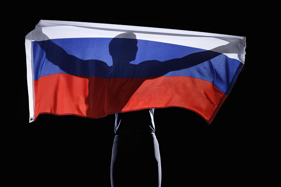 Silhouette of person holding flag of Russian Federation on black background Photograph by Paul Taylor