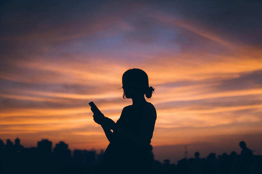 Silhouette of pregnant woman using mobile phone against dramatic sky during sunset Photograph by D3sign