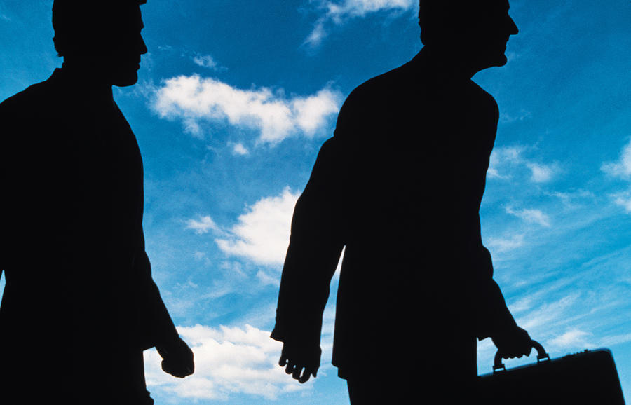 Silhouetted businessmen against sky Photograph by Comstock
