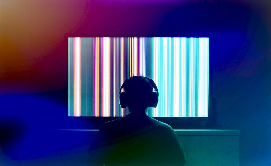 Silhouetted person with headphones watching large tv screen Photograph by Thomas Winz