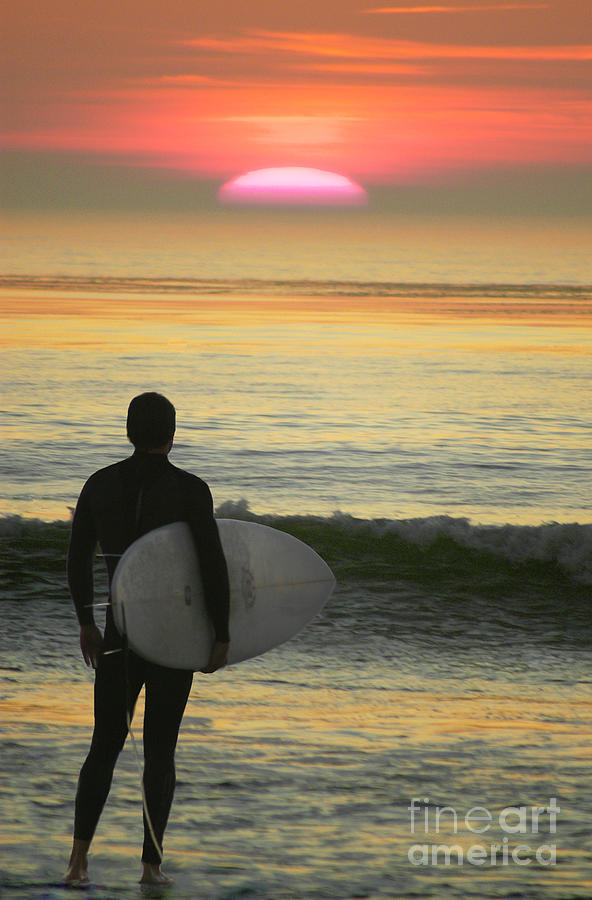 Silhouetted surfer looking out for waves at sunset. Photograph by Gunther Allen