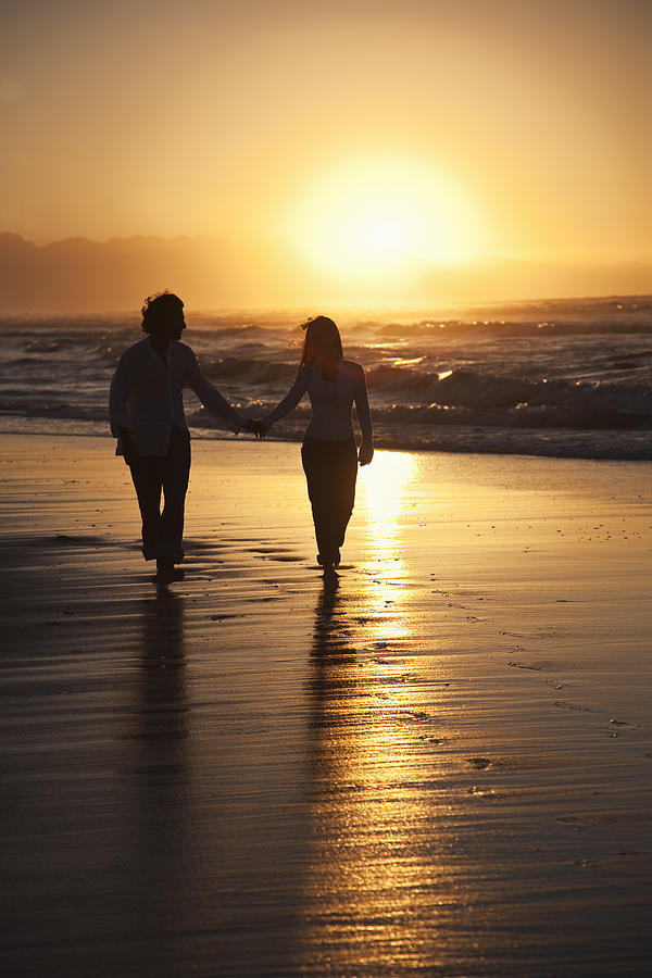 Silhoutte of Asian couple walking along beach Photograph by Martin Harvey