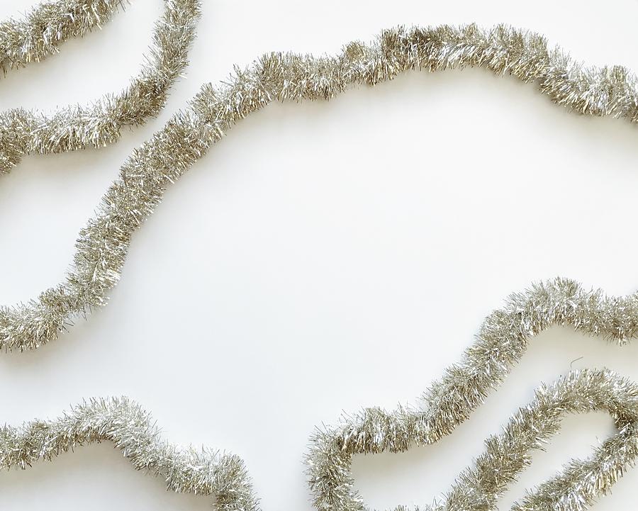 Silver tinsel on a white background Photograph by Michellealbert