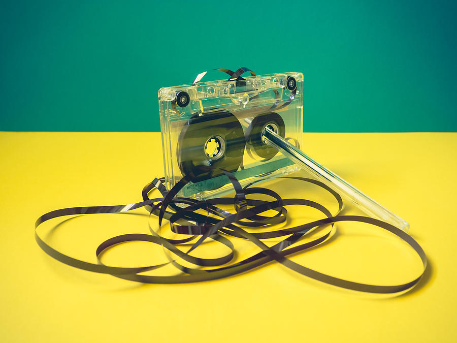 Single audio cassette tape with loose tape spilling from top cassette and a pen on vintage style Photograph by Ana Maria Serrano