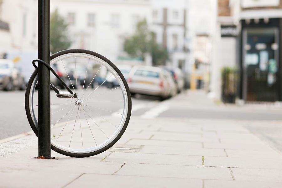 Single bicycle wheel secured to lamp post Photograph by Image Source