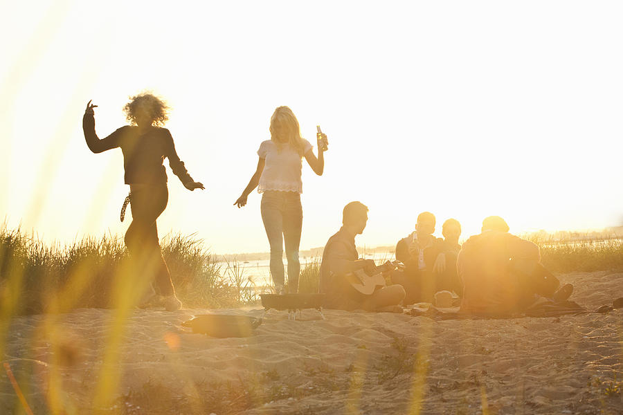Six adult friends partying at sunset on Bournemouth beach, Dorset, UK Photograph by Grant Squibb