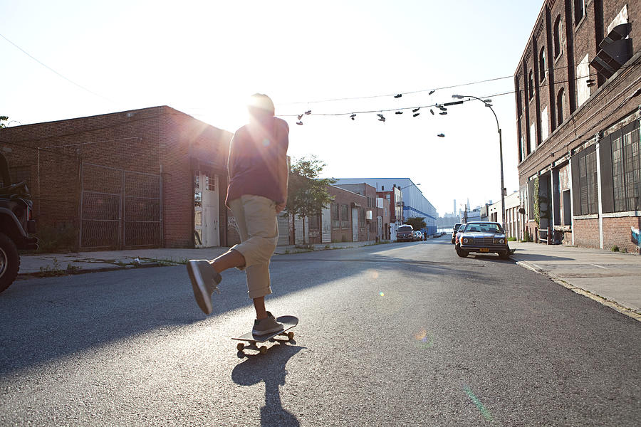 Skateboarder on urban street in sunlight Photograph by Image Source