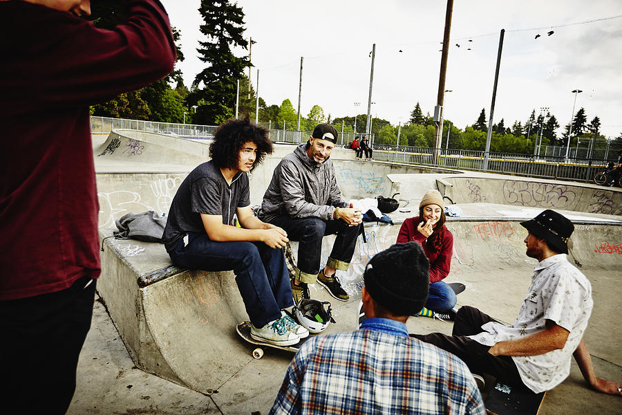 Skateboarders sitting in discussion in skate park Photograph by Thomas Barwick