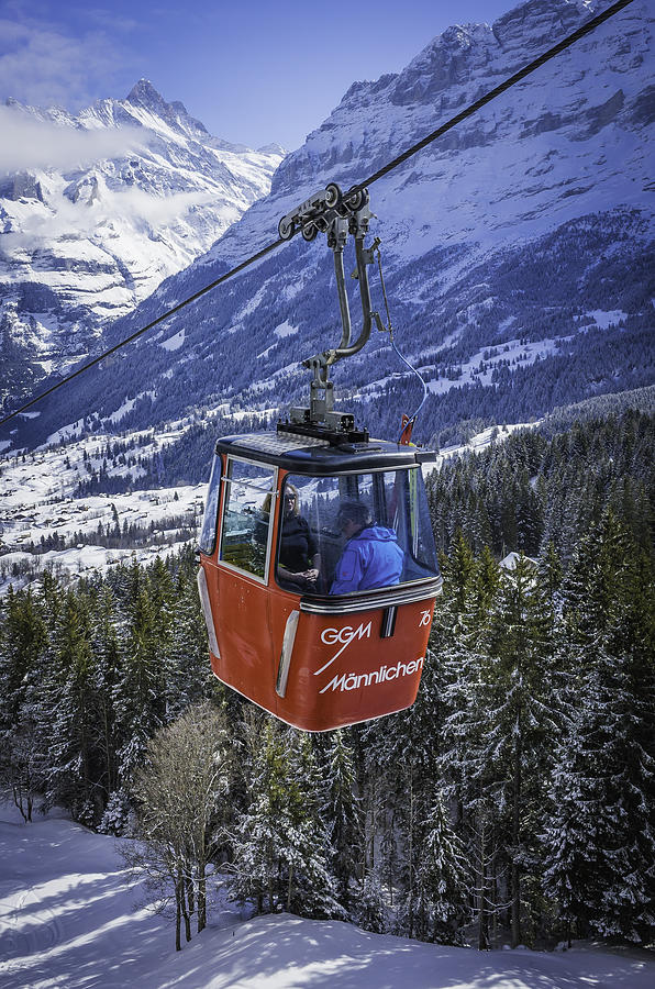 Skiers riding cable car above snowy Alpine mountain forests Switzerland Photograph by fotoVoyager