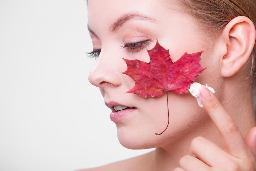 Skin care. Face of young woman girl with maple leaf. Photograph by Voyagerix