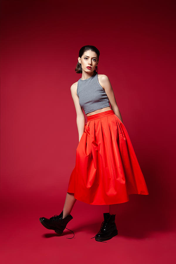 Skinny young woman in red skirt posing in studio Photograph by Iuliia Isaieva
