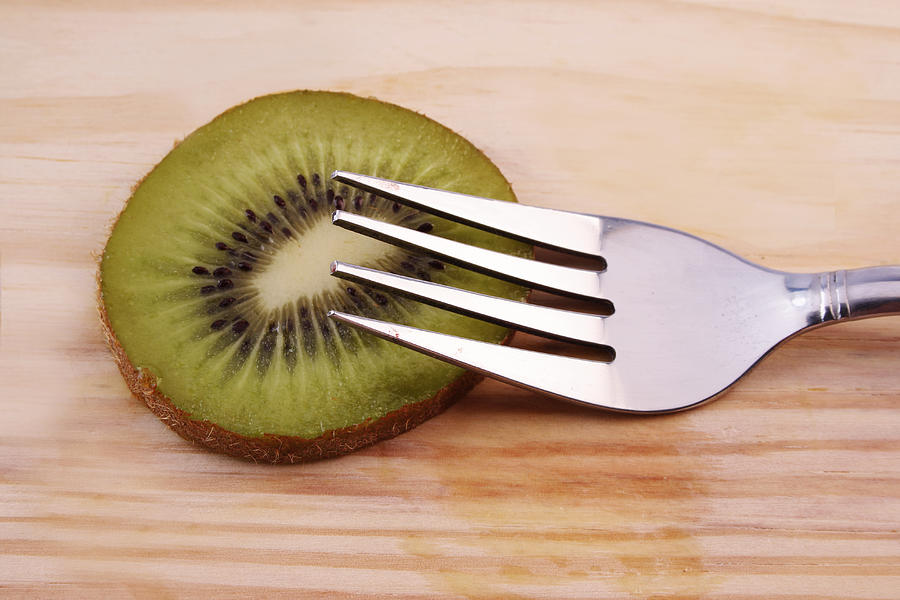 Slice of kiwifruit and a fork Photograph by Visage