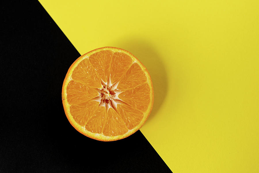 Slices of orange fresh Citrus orange fruit on a black and yellow background. Photograph by Michalakis Ppalis
