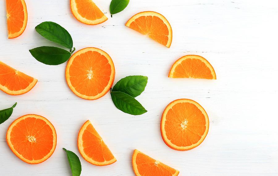 Slices of orange on white background. Flat lay, top view. Photograph by Yulia Naumenko