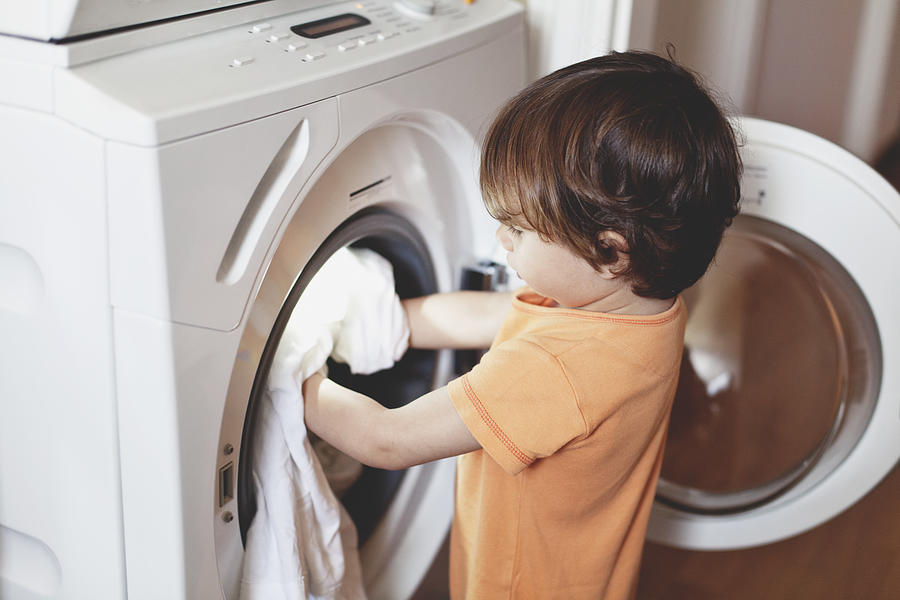 Small boy putting clothes in a washing machine Photograph by Thanasis Zovoilis