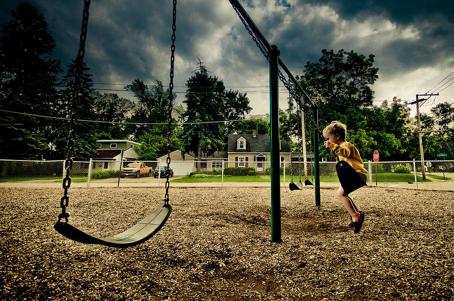 Small boy Swinging while storm clouds come in Photograph by Thomas Photography