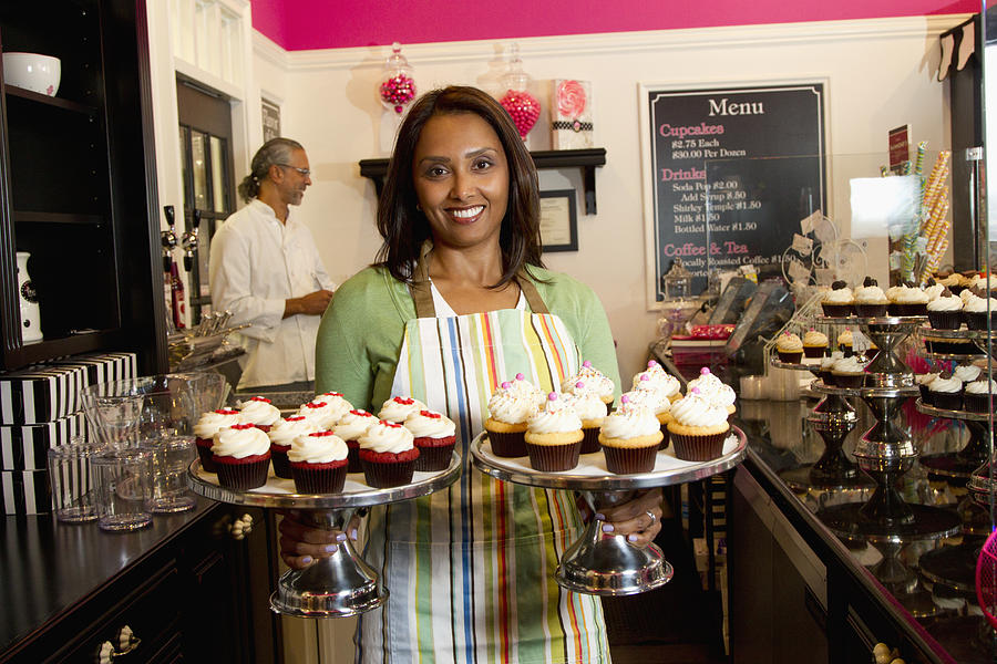 Small business owners with cupcakes in bakery shop Photograph by Jon Feingersh Photography Inc