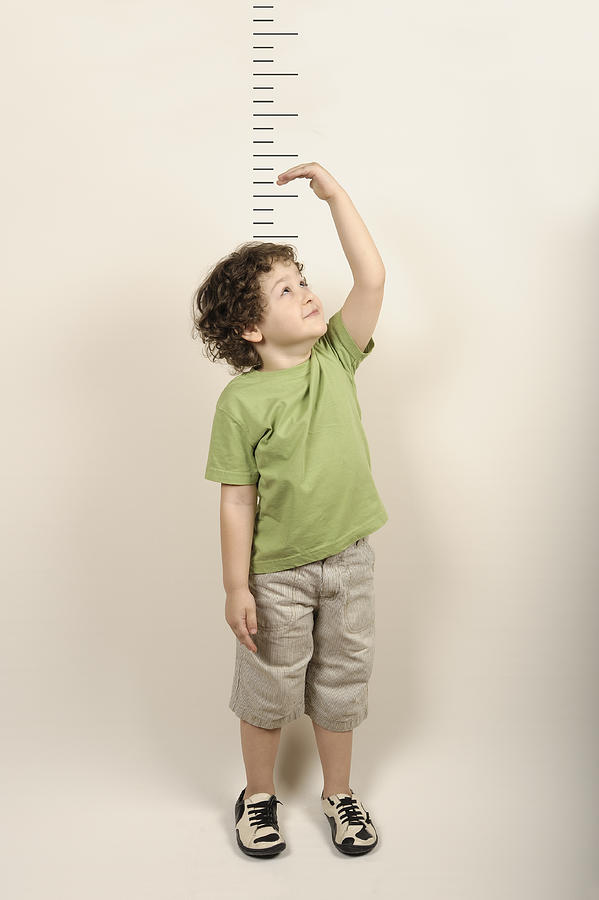 Small child measuring himself standing up Photograph by Xefstock