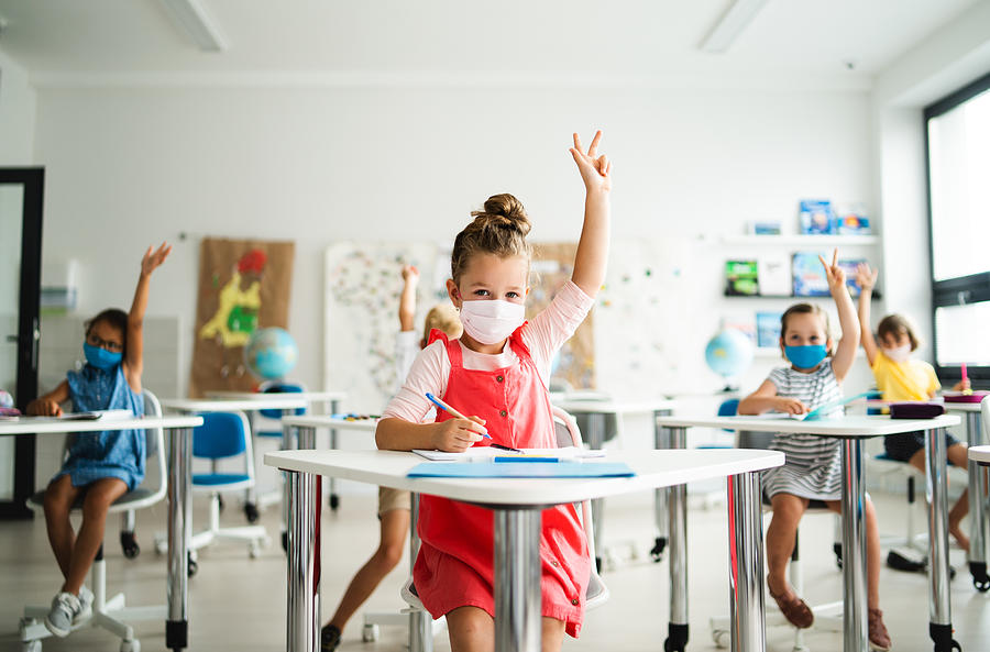 Small children with face mask back to school after coronavirus quarantine, learning. Photograph by Halfpoint Images