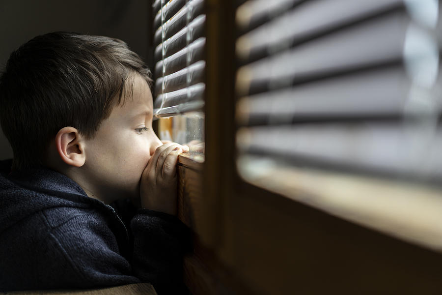 Small sad boy looking through the window during Coronavirus isolation. Photograph by Vladimir Vladimirov